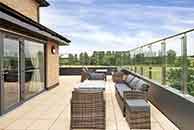 Spacious balcony with modern outdoor rattan garden furniture overlooking a green landscape