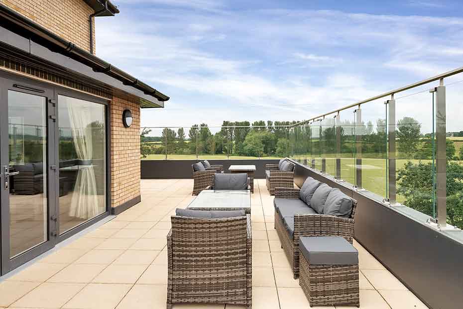 Spacious balcony with modern outdoor rattan garden furniture overlooking a green landscape