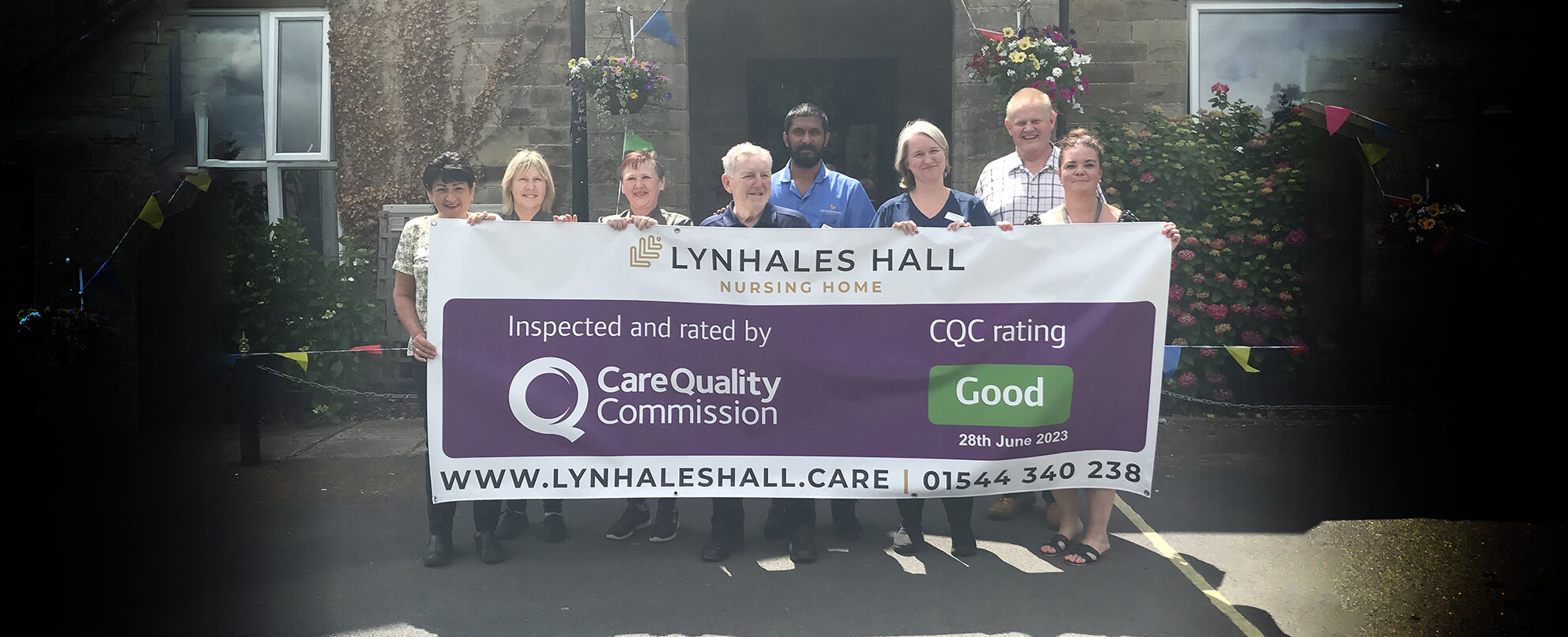 Staff and elderly people stand together and hold a banner with CQC 'good' rating