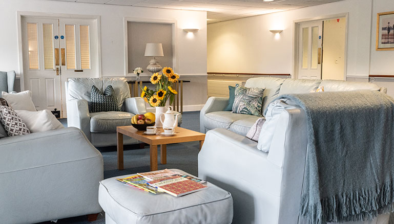 A cosy living room setting with two light grey sofas adorned with various patterned cushions and a wooden coffee table