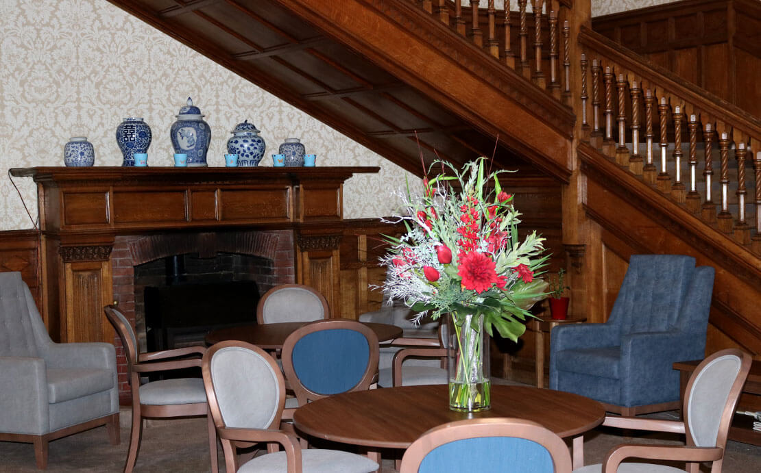 An elegant seating area with a wooden staircase, a fireplace, and a dining area